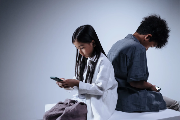 Two children play on their phones, unaware of the dangers that may lurk behind their screens.